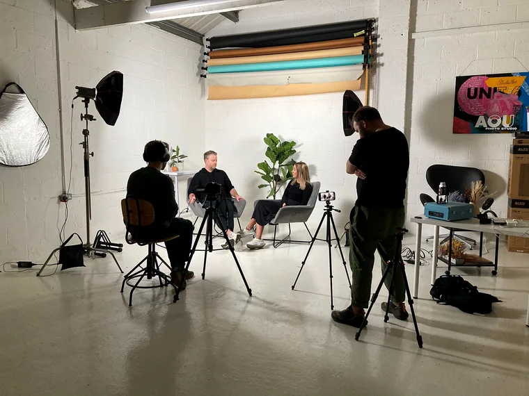 Behind the scenes on an interview shoot: lights, cameras and two guests in the studio