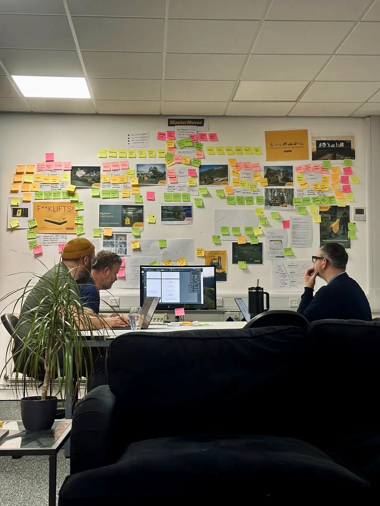 A planning wall covered in sticky notes and printouts in the studio