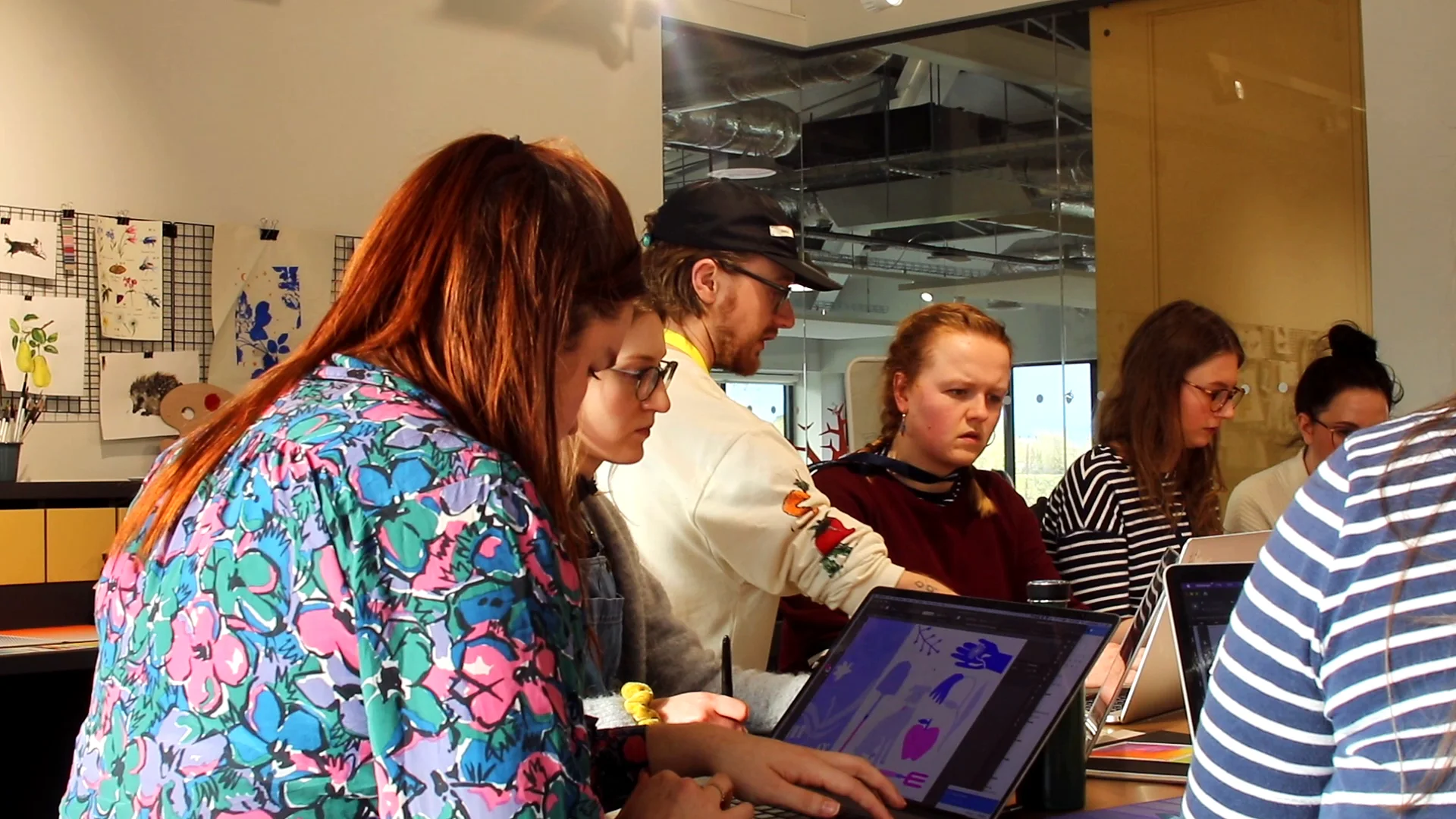 Team members in floral and striped tops drawing their designs on tablets