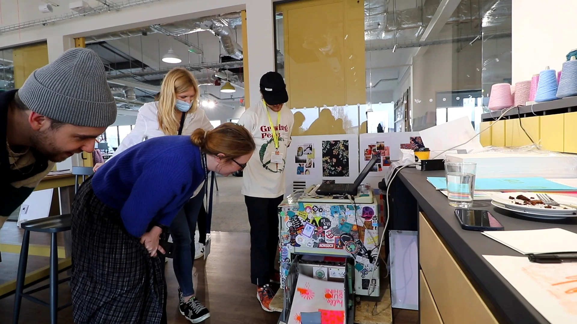 The team leans in to watch a print come off the risograph machine