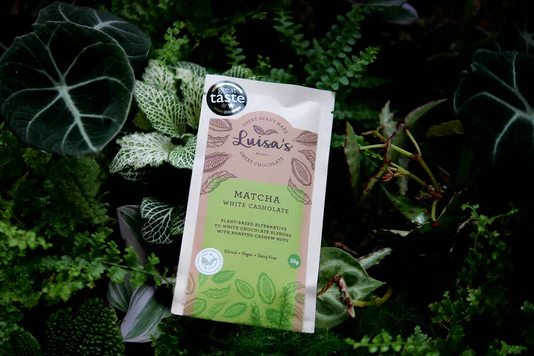 Luisa's Vegan Chocolates Matcha White Casholate pouch styled among ferns and tropical leaves