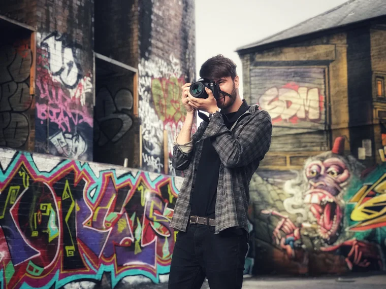 Luke Gray, Nottingham photographer and videographer, shooting with a Canon camera in front of colourful graffiti walls