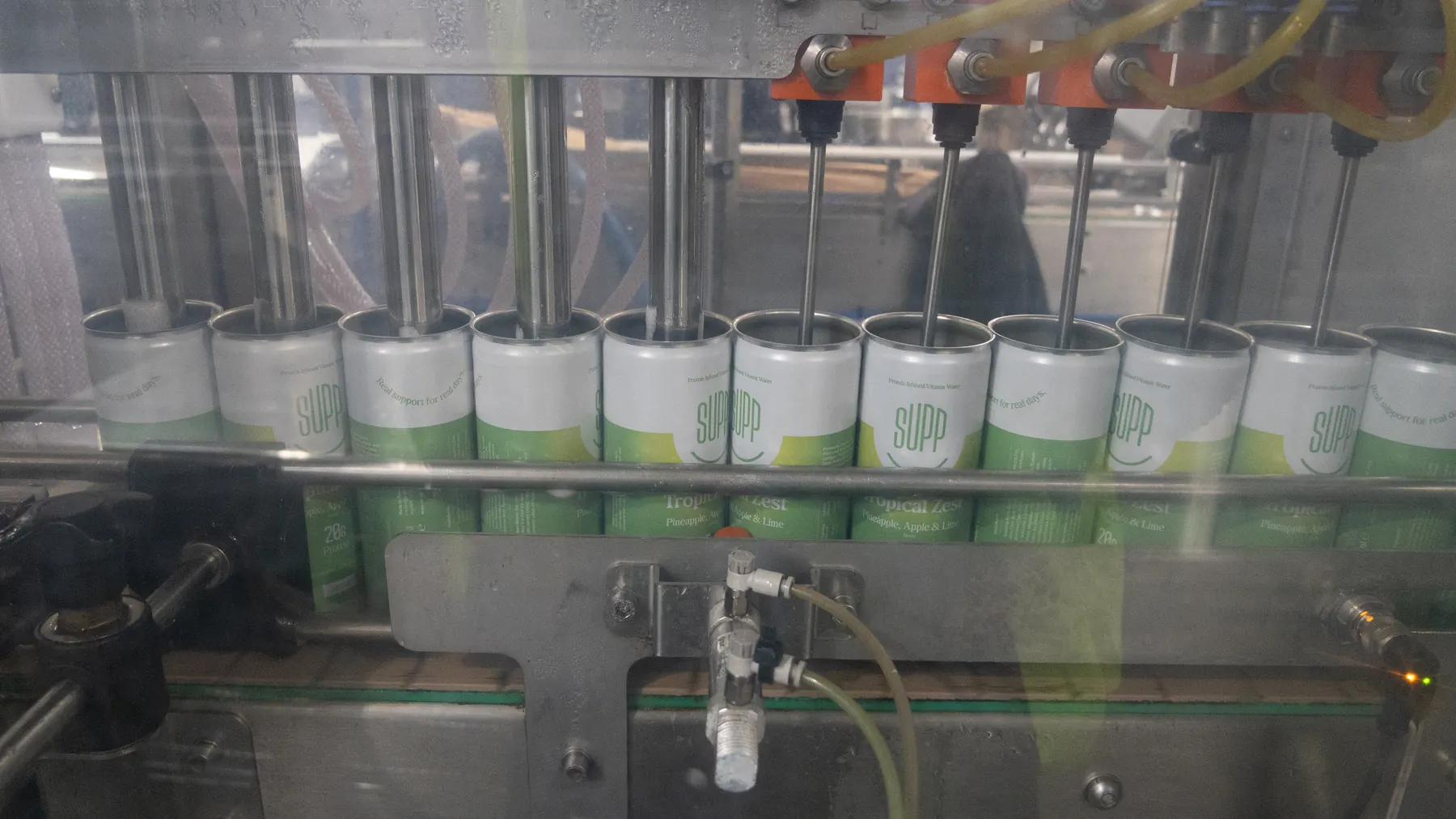 Supp cans moving through the filling machine on the production line