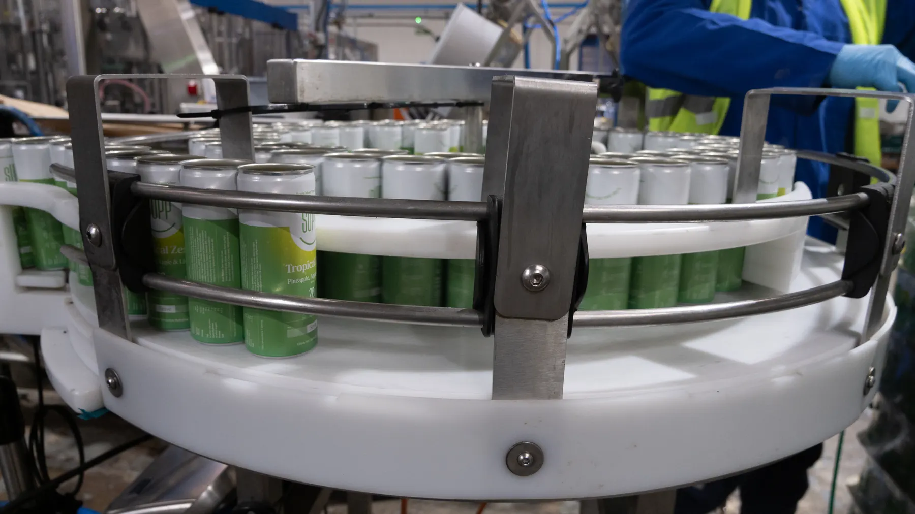 Operator in hi-vis guiding Supp cans around the canning line