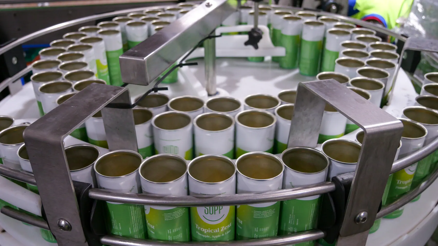 Rows of empty green Supp cans circling a rotary table on the canning line
