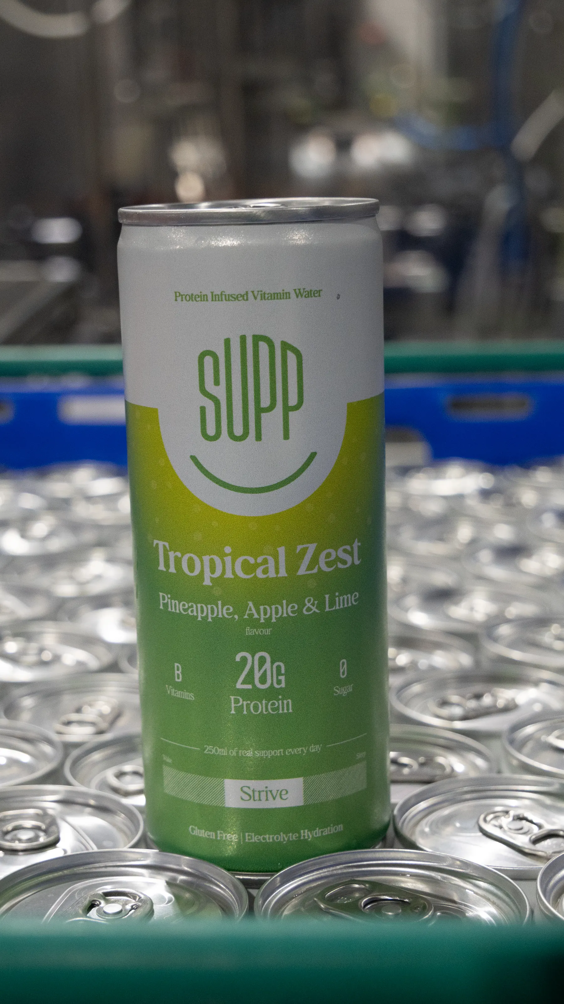 Supp Tropical Zest protein water can standing on a crate of empty cans, portrait crop