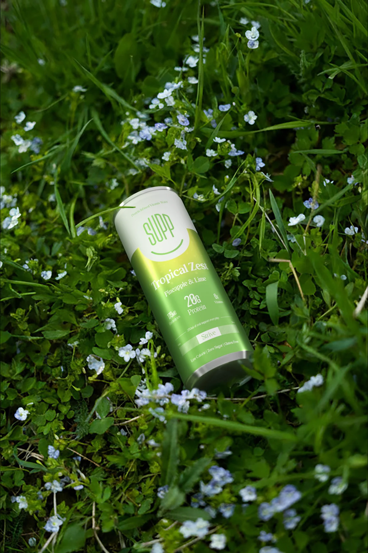 A Supp Tropical Zest can lying in long grass dotted with tiny white flowers