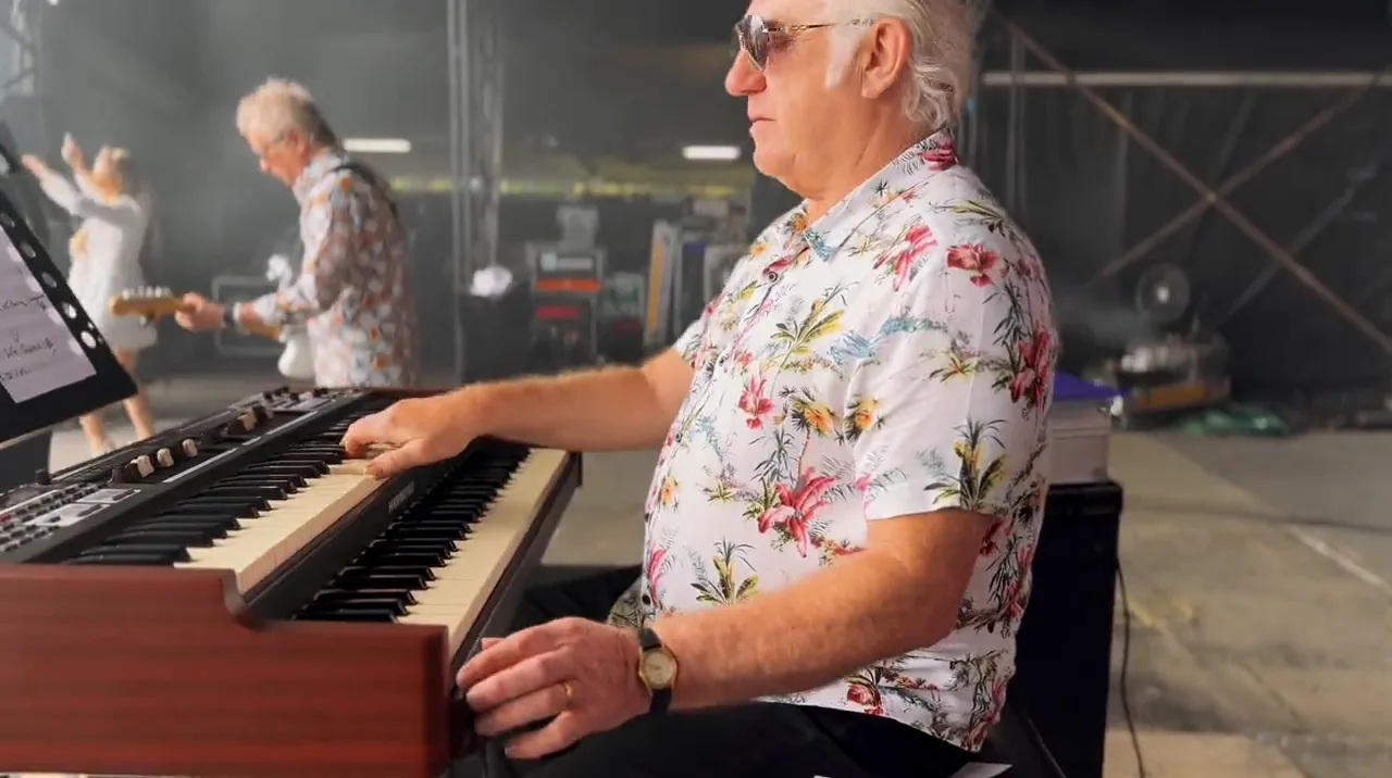 A keyboard player in a floral shirt and sunglasses playing a Hammond organ on stage